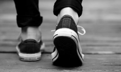 Persons sedd bakifrån, med fokus på hens skor.