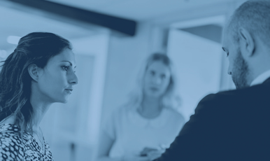 Tre personer på en arbetsplats pratar och ser allvarliga ut.