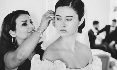 Ung kvinna förbereds inför bröllop av annan kvinna. Två män i bakgrunden.