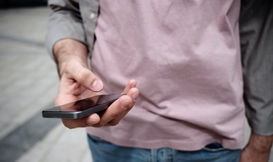 En person står och håller en mobiltelefon i handen.