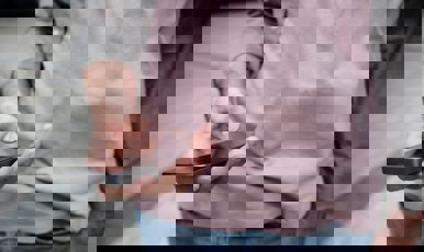 En person står och håller en mobiltelefon i handen.